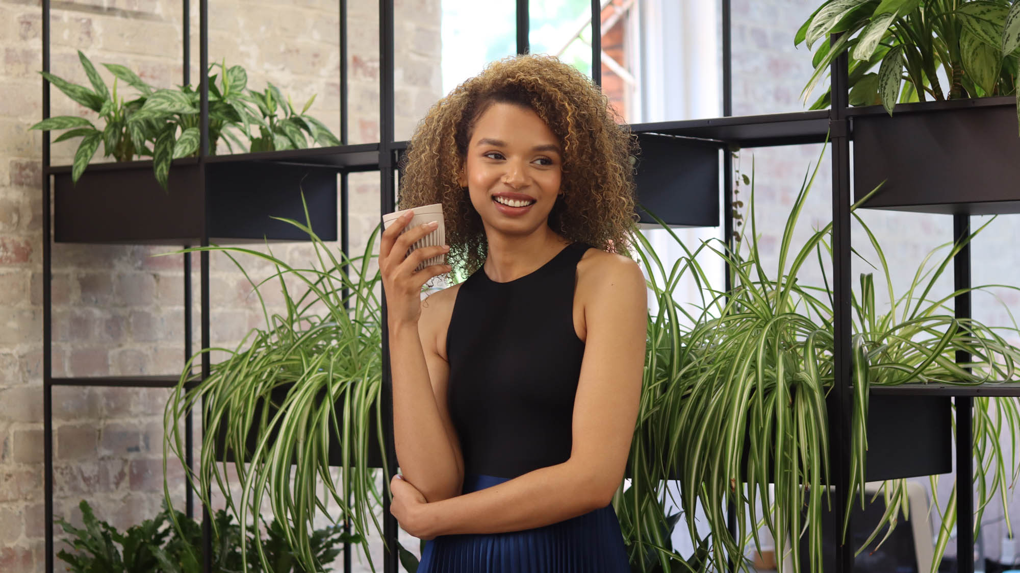 Coworker in coworking space The Loft Queen's Park with coffee next to plants