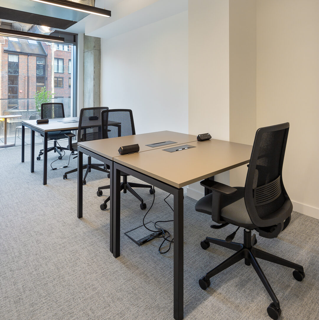 Modern private office for small teams in a coworking space in Putney, featuring ergonomic seating, large desks, and plenty of natural light from floor-to-ceiling windows.