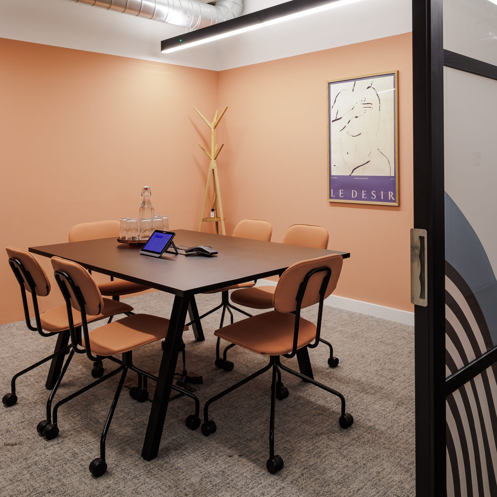 Modern meeting room in a stylish workspace Wandsworth location, featuring peach-toned walls, minimalist furniture, and glass partition with wave design.