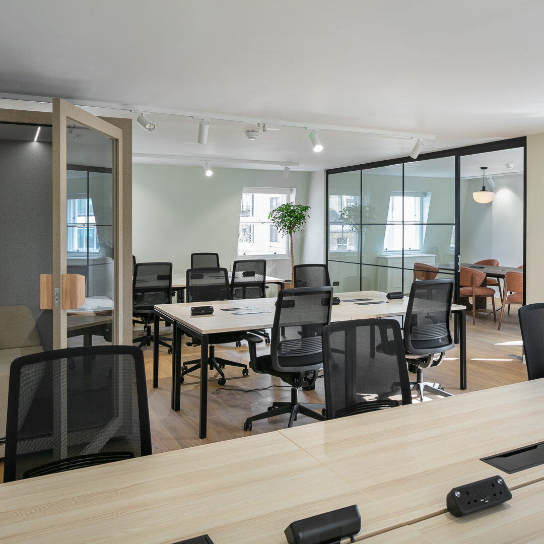Spacious and modern large serviced office in Marylebone, featuring collaborative desk space, ergonomic chairs, private phone booth, and a glass-partitioned meeting area flooded with natural light.