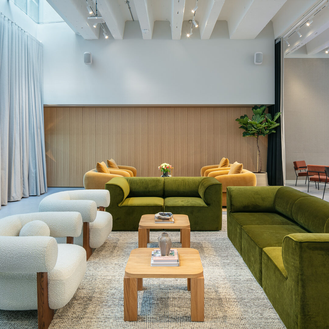 Stylish lounge and event space at Hale House, featuring velvet green and mustard seating, modern armchairs, a large presentation screen, and soft ambient lighting—ideal for talks, workshops, or networking events.